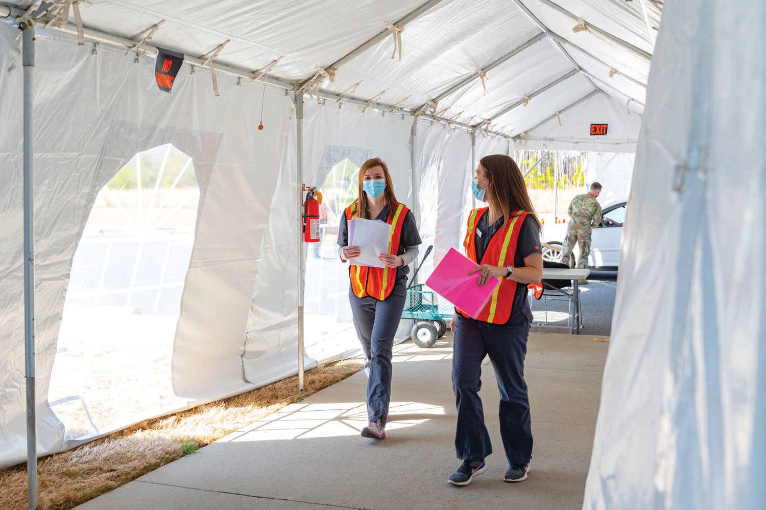 Julia Pitts (left) and Brianna Reeves, nursing students at UNC, act as runners for documents and materials from point to point — a critical component of the Chatham Ag Center's vaccine distribution operation, pictured here in March 2021.