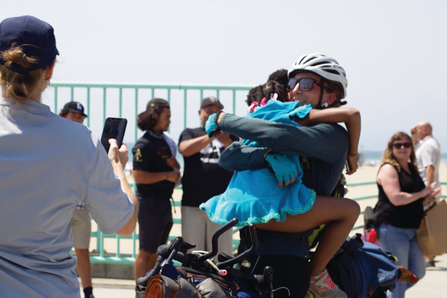 Pittsboro's Emmaus Holder (in white helmet) hugs his younger sister, Mia (in blue), after reaching the finish line of his cross-country cycling trip at a pier in Los Angeles. Holder's family traveled all the way to the West Coast to see him finish the journey on July 12.