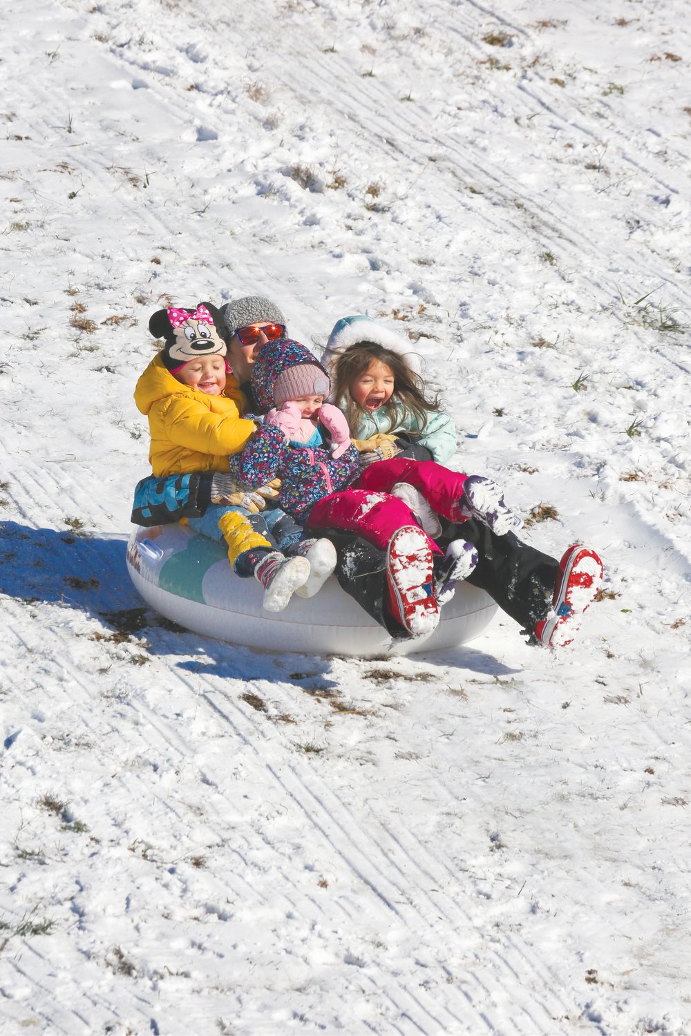 A tube provides a cushy trip down a snow-packed hill for these kids — and a supervising adult — in Briar Chapel.