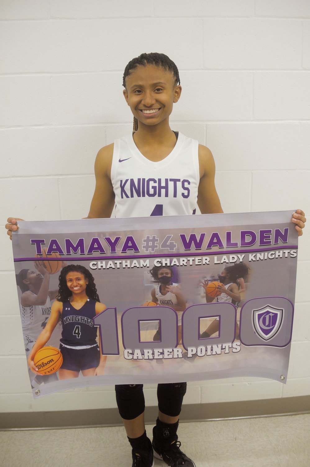Chatham Charter junior Tamaya Walden poses with a banner made in honor of her hitting her career milestone of 1,000 points after the Knights' win over Woods Charter on Feb. 8. She became just the third women's basketball player in school history to hit that mark.