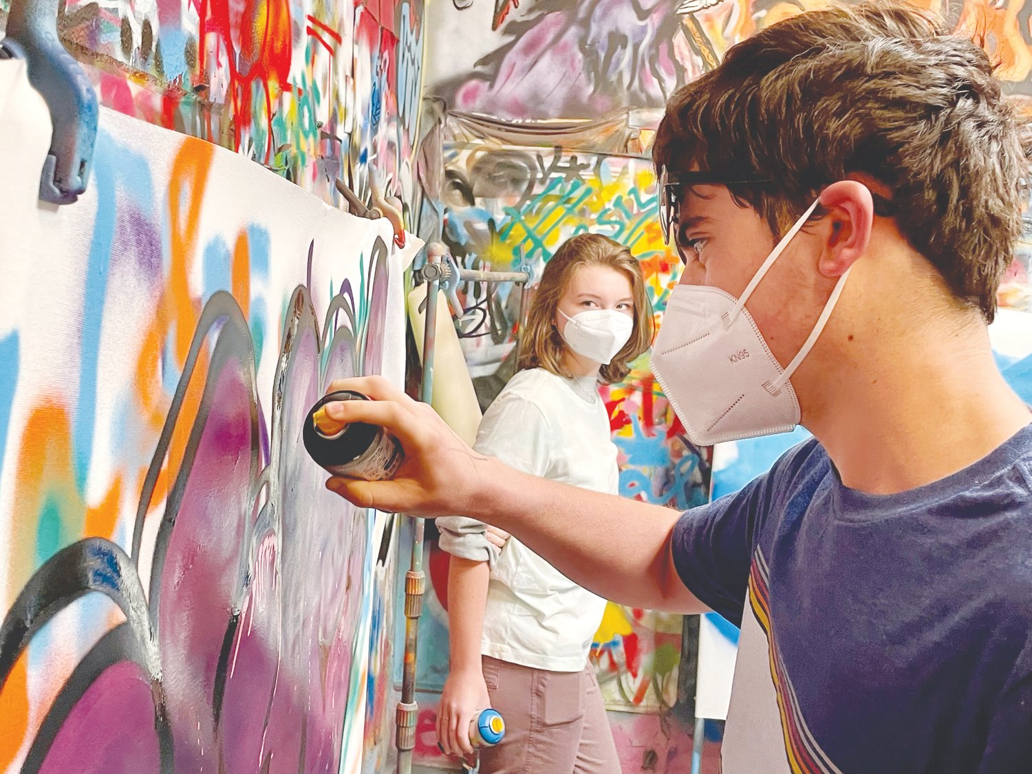 Louis Graham, right, gives graffiti technique a try as Emma Wieber watches. After learning about street art during a morning tour of the colorful Bushwick neighborhood in Brooklyn, acclaimed street artist Leaf taught J-M students some basic spray paint techniques and worked with them to create two large canvases.
