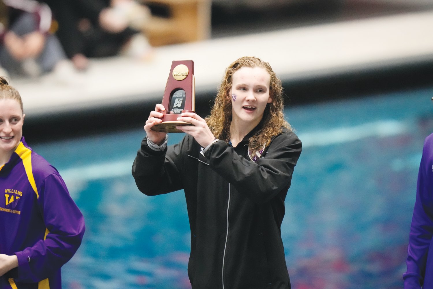 Kenyon swimmer Jennah Fadely hoists a trophy at the NCAA Division III Swimming & Diving National Championships. Fadely took 1st place in two relay races and 3rd place in two invidual breaststroke races.