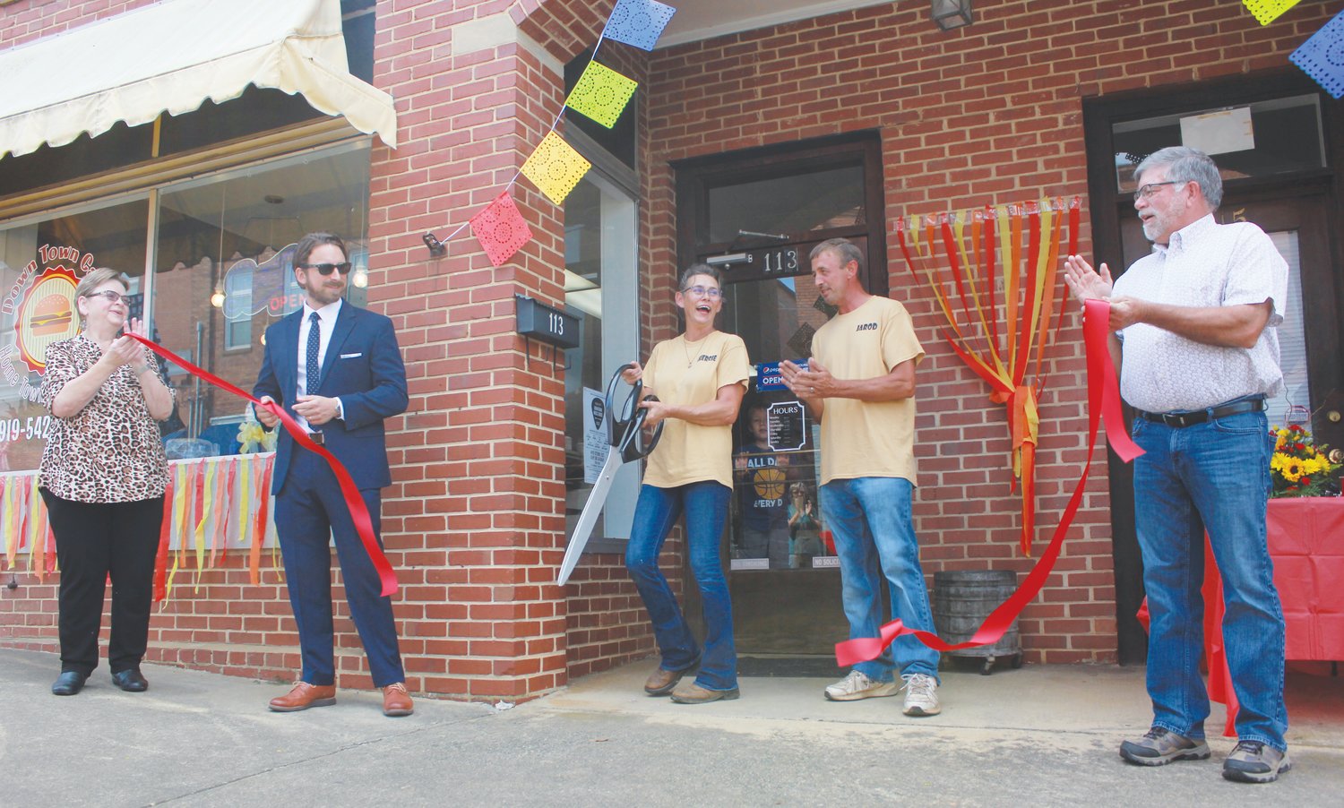 Down Town Cafe owner and operator Sherrie Hatfield, center, cuts the offical ribbon, commemorating the opening of her restaurant on Thursday in downtown Siler City. Mayor Chip Price (right) was also in attendance to celebrate.