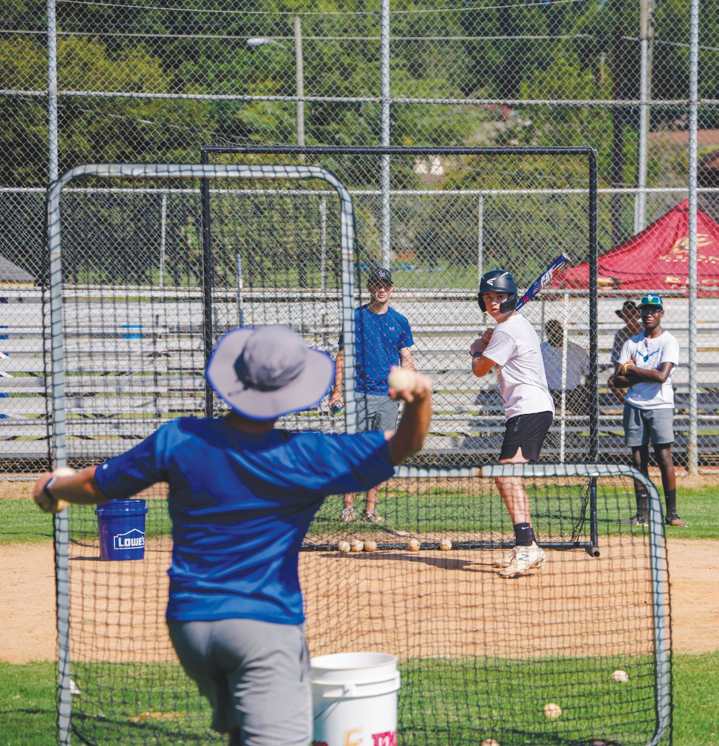 Jordan-Matthews assistant baseball coach Will Felder (front) throws a pitch behind the L-screen to camper Will Beck during the final day of the Jets' baseball camp last Thursday.