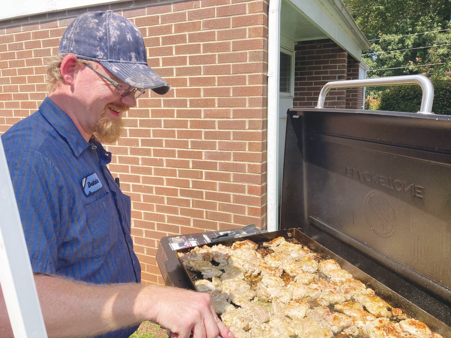 Love Chatham's Executive Director Dakota Philbrick works the grill at the organization's chicken plate fundraiser.