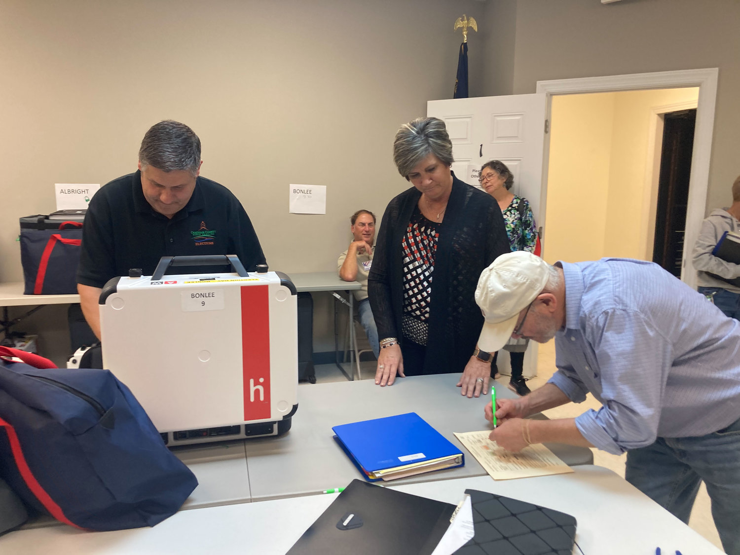 Election officials and board of elections staff work to ensure the tabulator from the Bonlee precinct isn't comprimised.