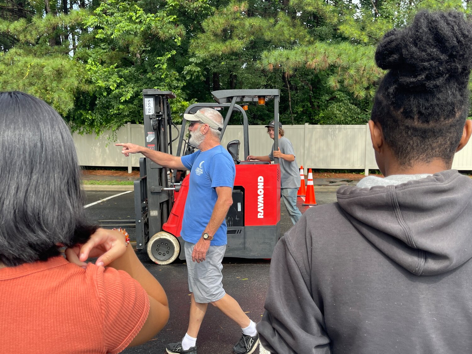 Forklift Instructor and Safety Coordinator Ben Rankin, wearing a blue shirt, continues to teach and instruct the students through the forklift course as attendees observe.